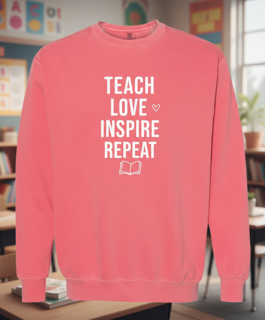 Pink sweatshirt with 'Teach Love Inspire Repeat' text on a white background